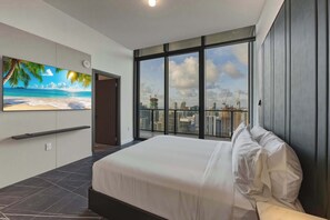 A modern hotel room with a large bed, a city view through floor-to-ceiling windows, a flat-screen TV on the wall, and a balcony with a cityscape view. - Presidential Penthouse Private Infinity Pool (Miami)