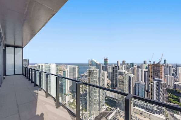 Ein Balkon mit Blick auf die Stadt, hohe Gebäude und ein klarer Himmel.