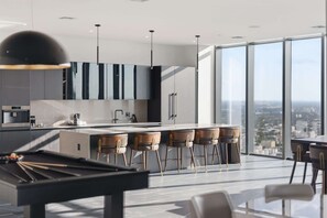 A modern kitchen with a central island, bar stools, and a pool table. - Luxury Penthouse E11even Top Floor w Private Pool (Miami)