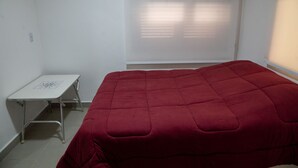 A room with a bed, a small table, and a window with blinds. - Casa P na Areia com Cen rio Privilegiado Guaec (São Sebastião)