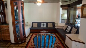 A living room with a sofa, a decorative chair, a cabinet, and a view of the outside. - Casa P na Areia com Cen rio Privilegiado Guaec (São Sebastião)