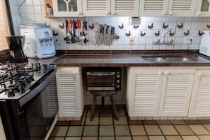 Eine Küche mit Gasherd, Kaffeemaschine und einem Toaster auf einem Standfuß.