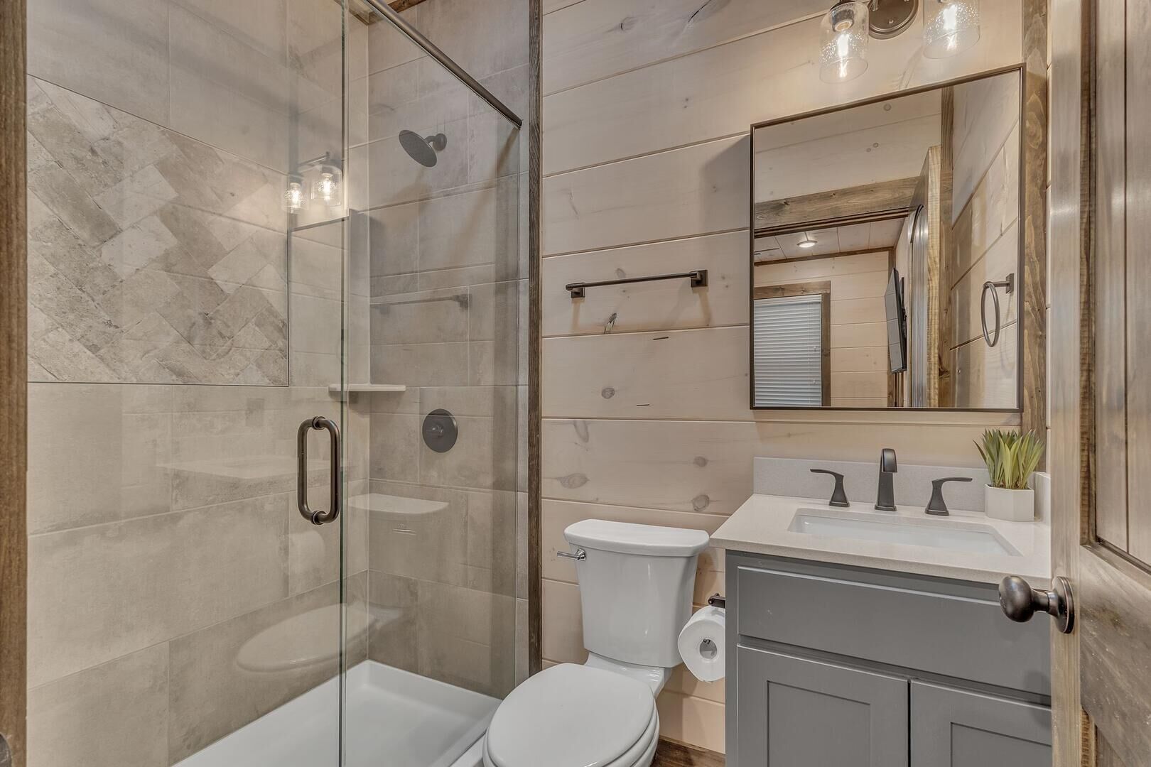 Un bagno moderno con doccia vetrata, un water e un mobile lavabo con specchio.