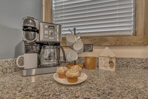 Eine Küche mit Kaffeemaschine, einem Teller mit Muffins und einer Holzdeko.