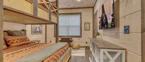 A cozy room with a bunk bed, a desk, and a TV.