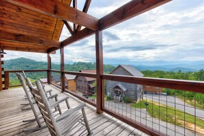 Eine Holzdielen-Terrasse mit Blick auf eine ländliche Landschaft, einschließlich Häusern und Bergen.