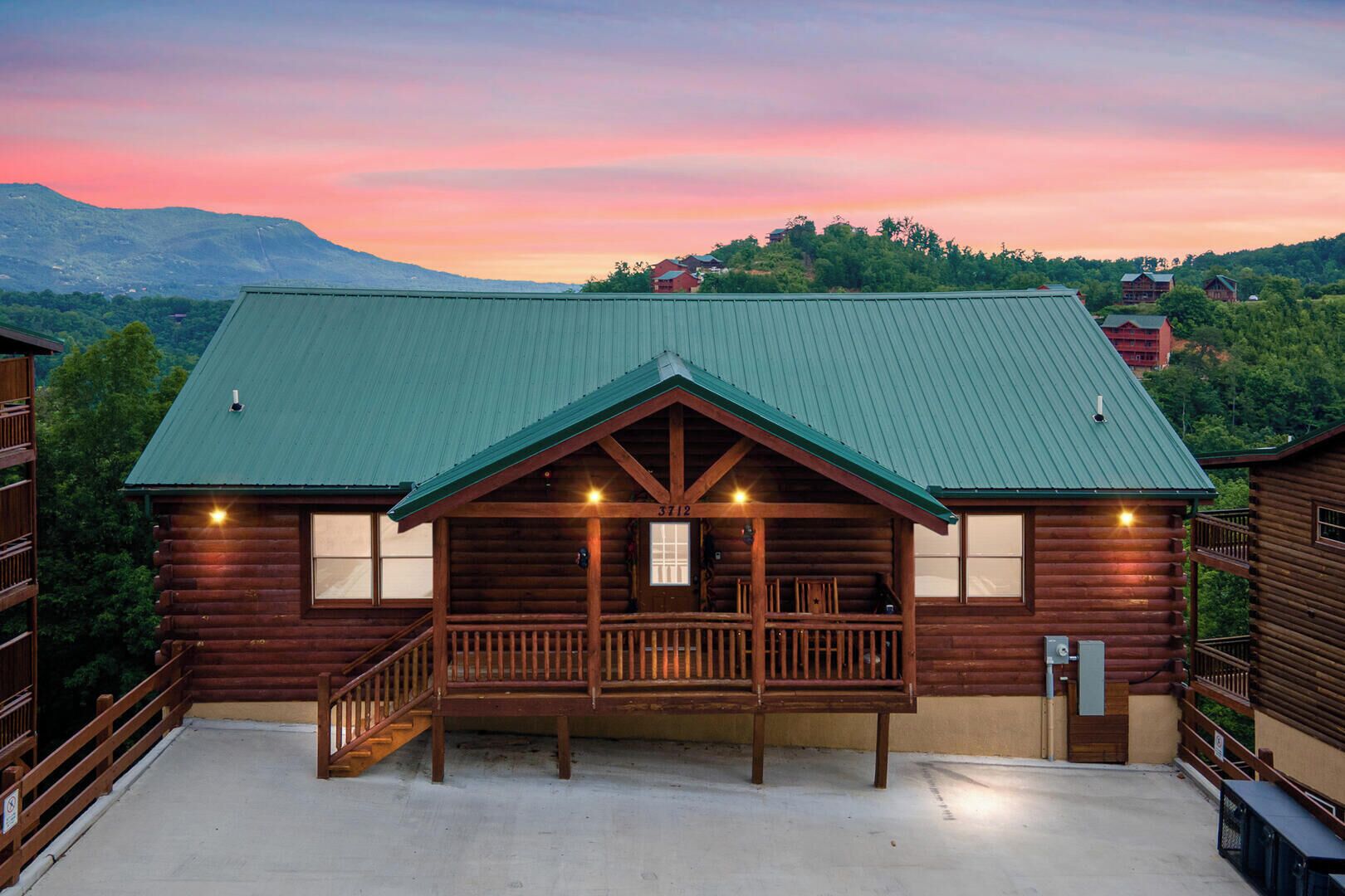 A log cabin-style building with a green roof, a porch, and a view of a mountainous landscape.