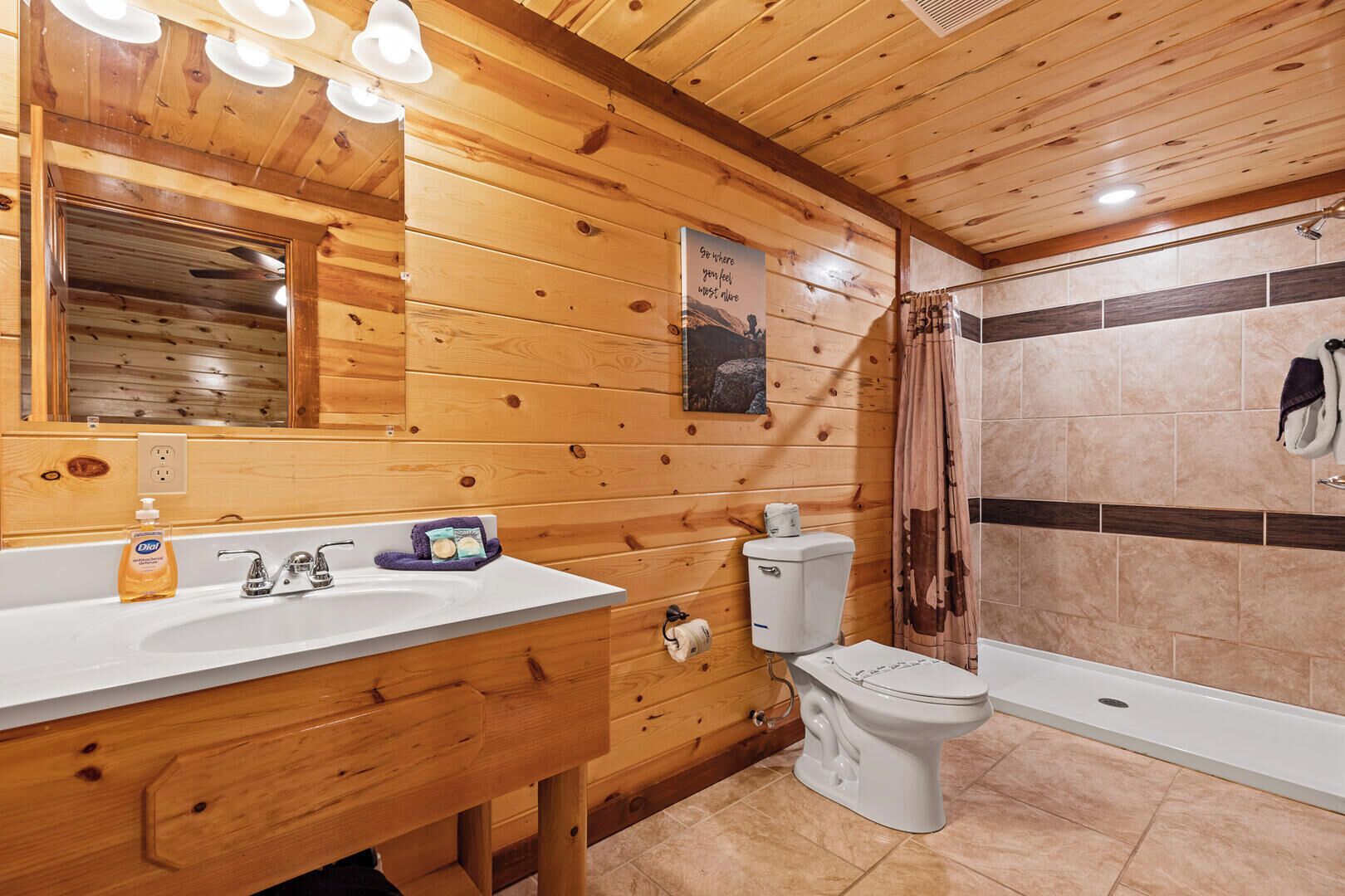 A wooden cabin bathroom with a sink, toilet, and shower.