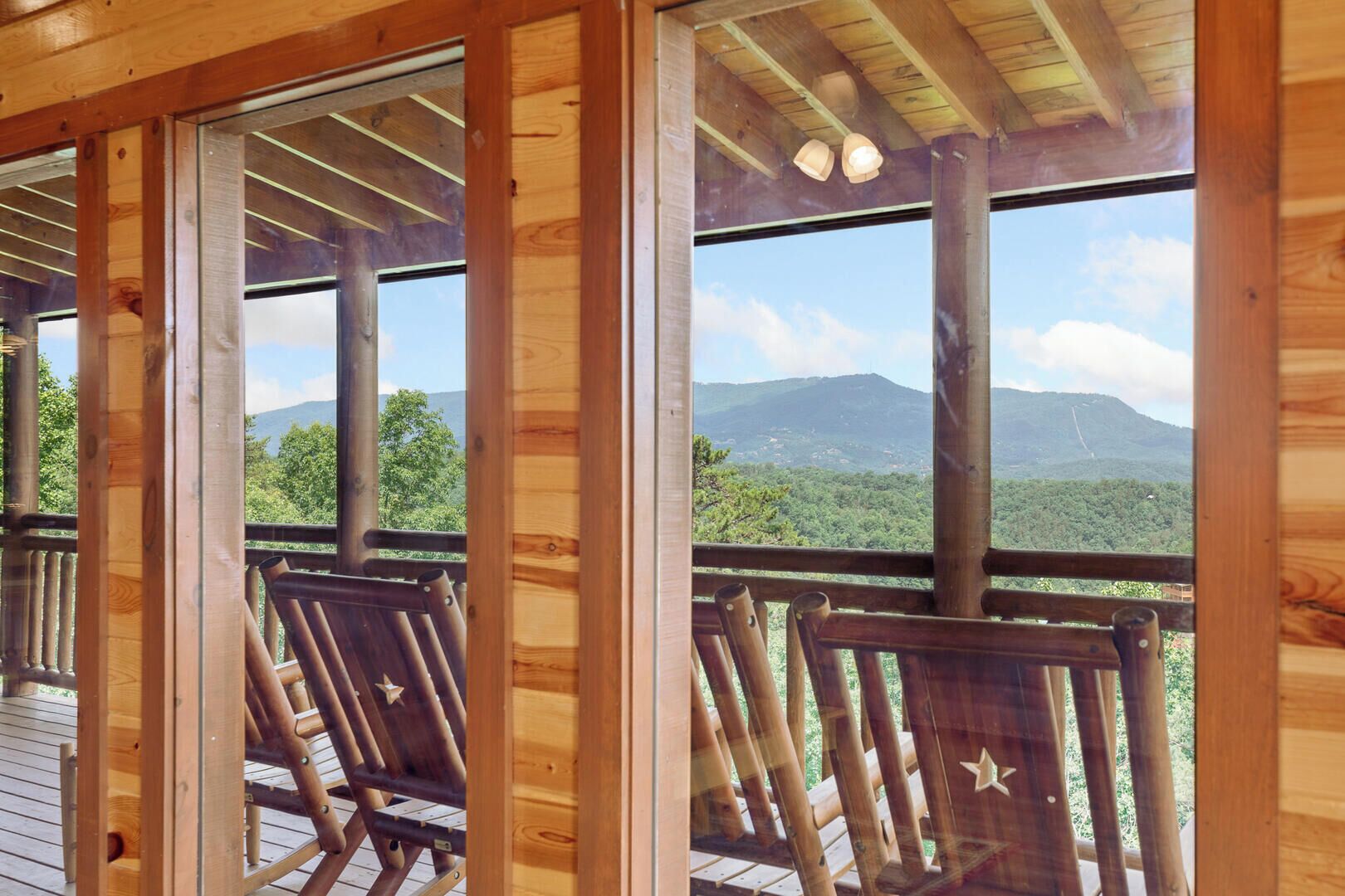 A wooden deck with chairs and a view of a mountain range.