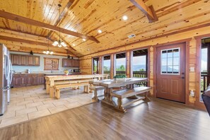 A spacious kitchen with wooden beams, a large island, and a view of the outdoors. - A Luxury Mountain Oasis for Families, Retreats & Group Getaways (Sevierville)