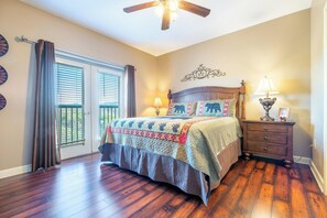 A bedroom with a bed, a nightstand, a lamp, a ceiling fan, and a window with blinds. - Mountain View Condo 5702 (Pigeon Forge)