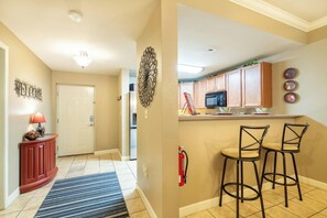 A hallway with a welcome sign, a red console table with a lamp, a blue striped rug, and a fire extinguisher. - Mountain View Condo 5702 (Pigeon Forge)