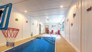 An indoor swimming pool with a basketball hoop, red chairs, and decorative wall art. - Welcome to This4br/4ba Where Modern Luxury and Memories Come Together! (Sevierville)