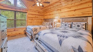 A wooden cabin bedroom with a bed, two nightstands, a dresser, a ceiling fan, and a window. - Welcome to This4br/4ba Where Modern Luxury and Memories Come Together! (Sevierville)