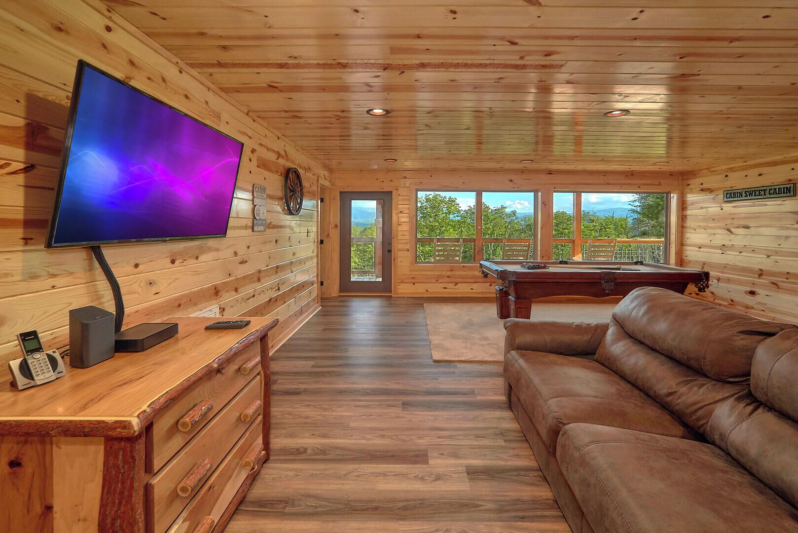 Interno di una baita in legno con televisore, tavolo da biliardo e divano in pelle.