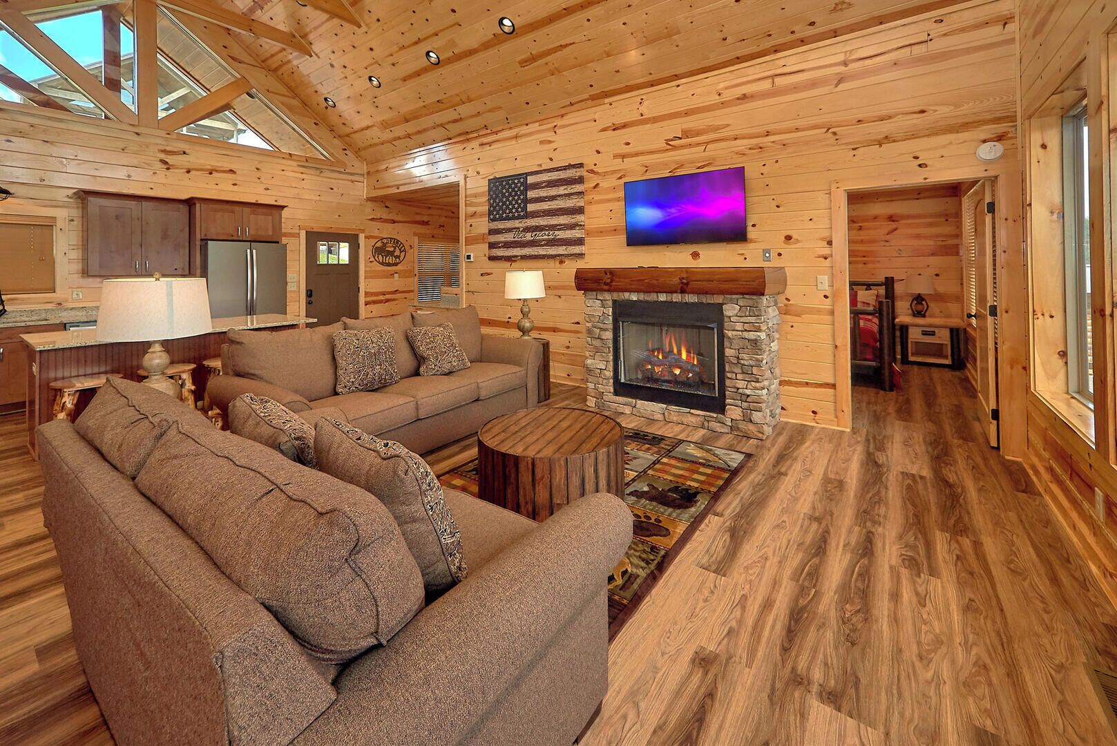 Un intérieur de chalet chaleureux avec une cheminée, des murs en bois, un canapé et un téléviseur.