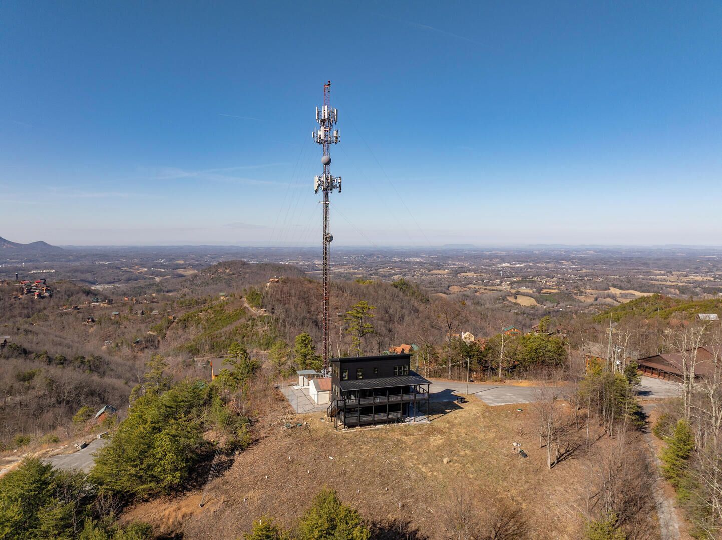 Ein Telekommunikationsturm mit einem Gebäude an der Basis, eingebettet in eine hügelige Landschaft.