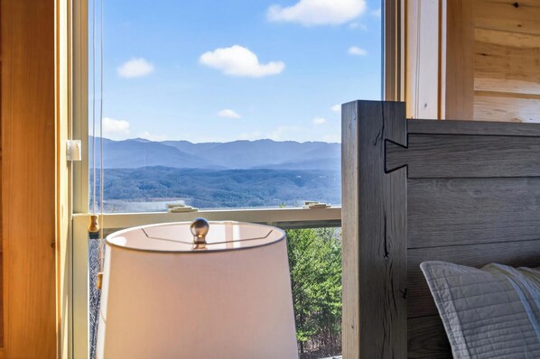 A room with a view of mountains, a wooden headboard, and a lamp. - Mountain Spirits (Sevierville)