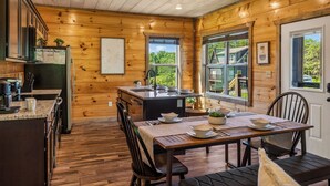 A wooden cabin interior with a kitchen, dining area, and large windows. - New! Indoor Pool, Game Room, Families Welcome! (Sevierville)