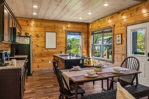 A wooden cabin interior with a kitchen, dining area, and large windows. - New! Indoor Pool, Game Room, Families Welcome! (Sevierville)