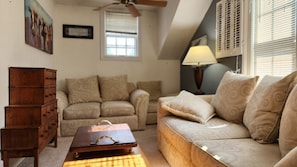 A living room with a wooden chest of drawers, a sofa, a patterned rug, and a ceiling fan. - Lovely 1-bedroom apartment with AC in charming Woodstock (Woodstock)