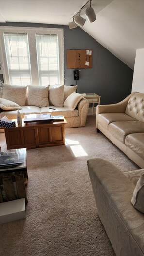 A living room with a beige sofa, a wooden coffee table, and a carpeted floor.