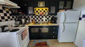 A kitchen with black cabinets, a white refrigerator, a checkered backsplash, and a red toy car on the floor.