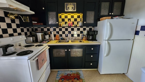 A kitchen with black cabinets, a white refrigerator, a checkered backsplash, and a red toy car on the floor.