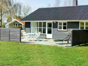 Ein modernes Haus mit Terrasse, einem Esstisch und einem Lounge-Sessel.