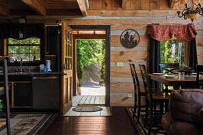 Un intérieur en bois comprenant une cuisine, un coin repas et une vue sur l’extérieur.