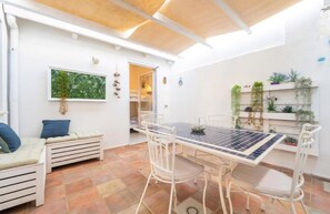 A compact living space with a dining table, chairs, a bench, and a small garden area with plants.