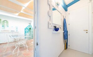A hallway with a white door, a blue wall, and a white ceiling with wooden beams.