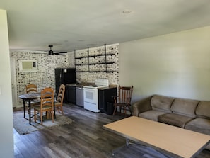 Un espace de vie compact comprenant une kitchenette, un coin repas et un coin salon.