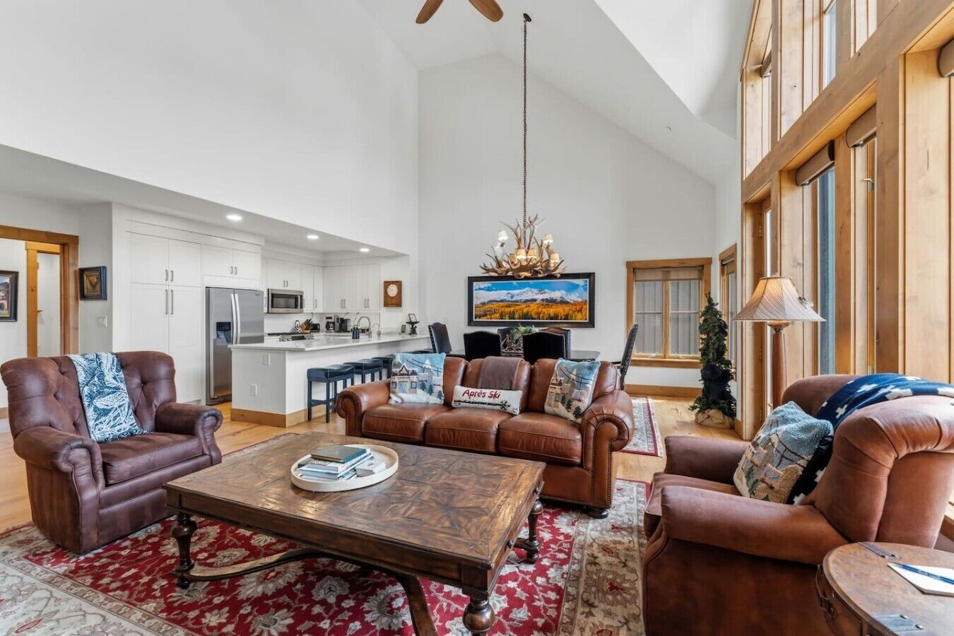 A spacious living area with leather sofas, a wooden coffee table, and a large window.