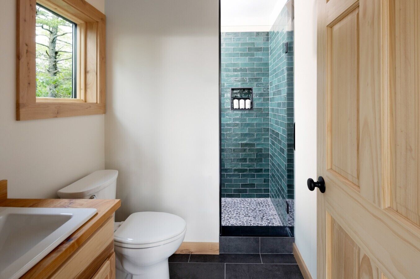 A bathroom with a toilet, sink, and a window.