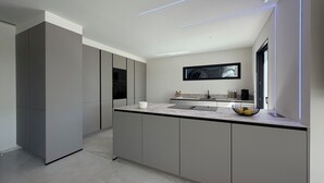 Una cocina moderna con una isla grande, electrodomésticos integrados y un televisor de pantalla plana montado en la pared.