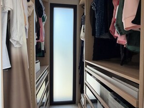 A walk-in closet with hanging and folded clothes, wooden shelving, and a sliding door. - Villa Lamartine with heated pool, 10 minutes from the beach and downtown—BRAND-NEW … (Provence-Alpes-Côte d'Azur)