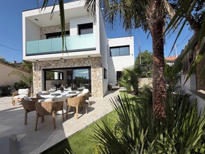 A modern two-story house with a patio, outdoor furniture, and a stone wall. - Villa Lamartine with heated pool, 10 minutes from the beach and downtown—BRAND-NEW … (Provence-Alpes-Côte d'Azur)
