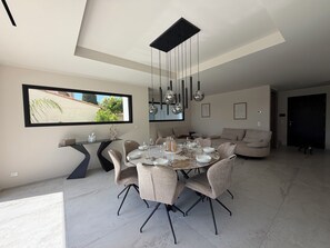 A modern dining area with a round table, chairs, and hanging pendant lights. - Villa Lamartine, 10 minutes from the beach and downtown—BRAND-NEW … (Provence-Alpes-Côte d'Azur)