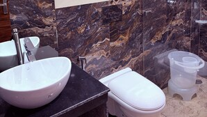Un baño con lavamanos, inodoro y zona de ducha.
