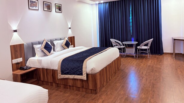 Una habitación de hotel con cama, lámparas de noche, escritorio, una silla y una mesita.