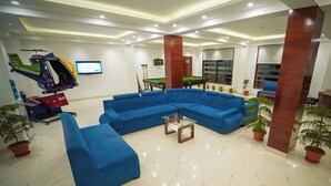Un lobby moderno con un sofá seccional azul, una mesa de billar y un helicóptero montado.
