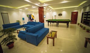 A hotel lobby with blue sofas, a pool table, and potted plants. - The Euphoria Grand (Shimla)