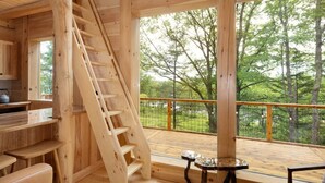 Ambiente in legno con una scala, un angolo cottura e una terrazza vista alberi.