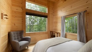 Una stanza in legno arredata con un letto, una sedia e un tavolo.