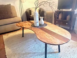 Una mesa redonda de madera con tapa de mármol, dos jarrones blancos y una base de metal negro.