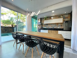 Eine moderne Küche mit einem Holztisch, schwarzen Stühlen, einer gefliesten Spritzschutzwand und einem Kühlschrank.