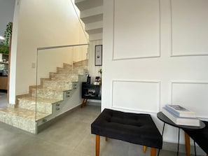 Ein modernes Interieur mit einer Treppe, einem schwarzen Hocker und einem kleinen Tisch mit einem Buch.