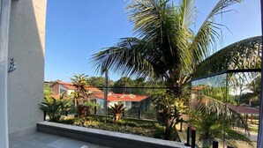 Un balcón con vista a una zona residencial, que incluye casas y palmeras.