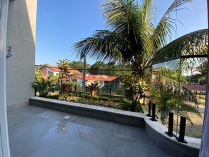 Ein Balkon mit Blick auf eine Wohngegend, darunter Häuser und Palmen.